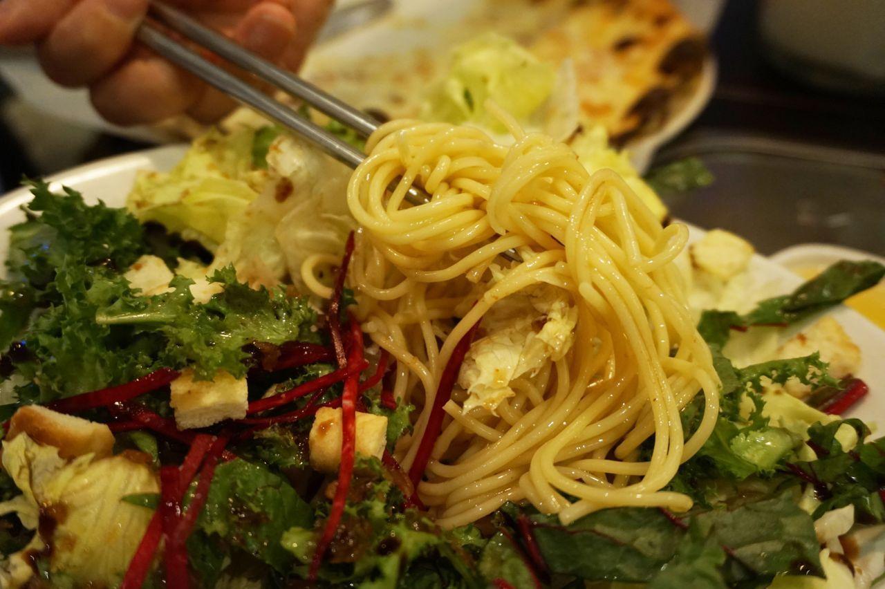 A forkful of salad pasta being lifted, capturing the blend of noodles and fresh greens in delicious harmony at Hwa Tteok.